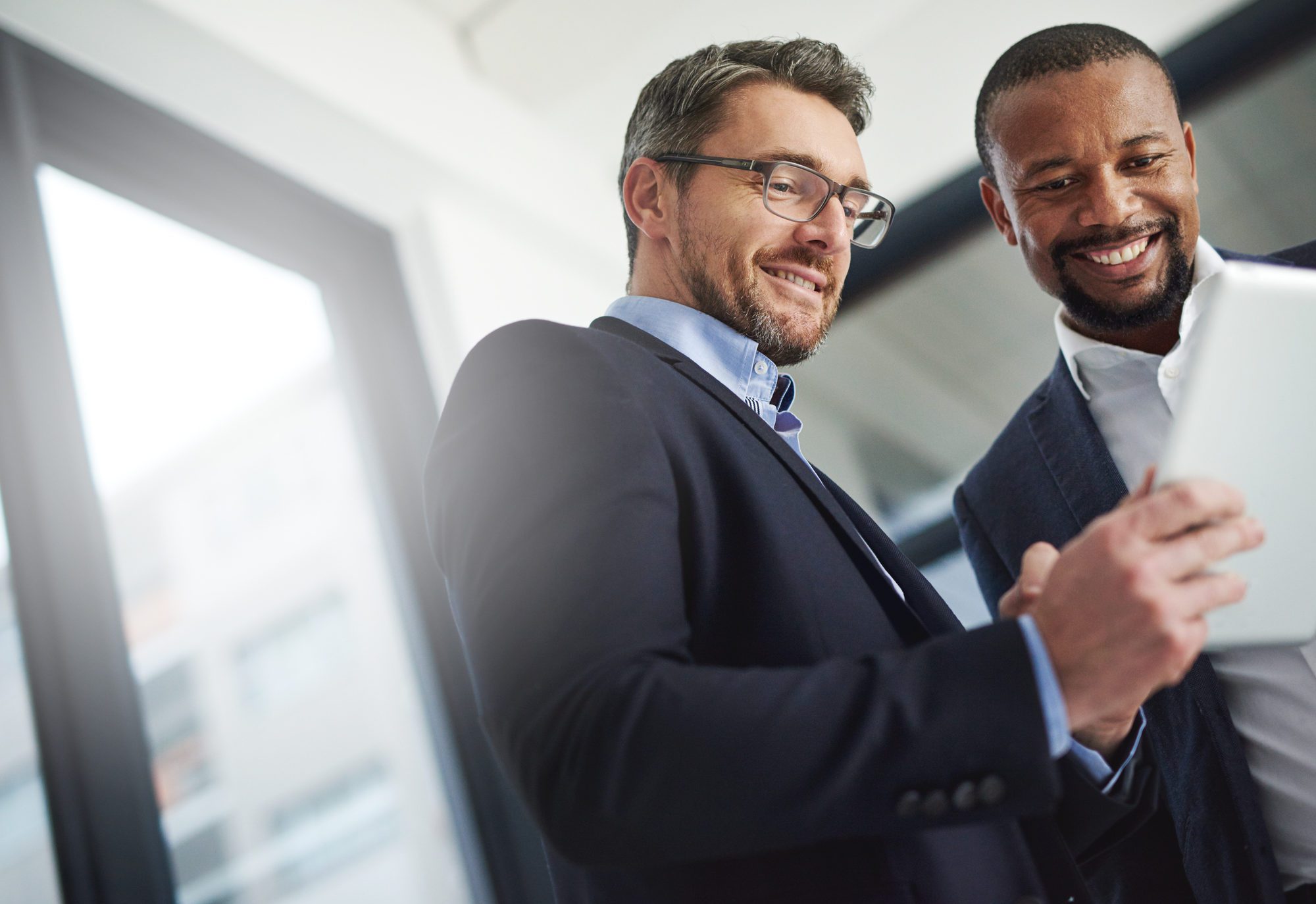 learning and transformation - Two men in suits looking at a tablet