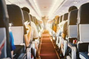 passenger seat, Interior of airplane with passengers sitting on seats and stewardess walking the aisle in background. Travel concept,vintage color,selective focus