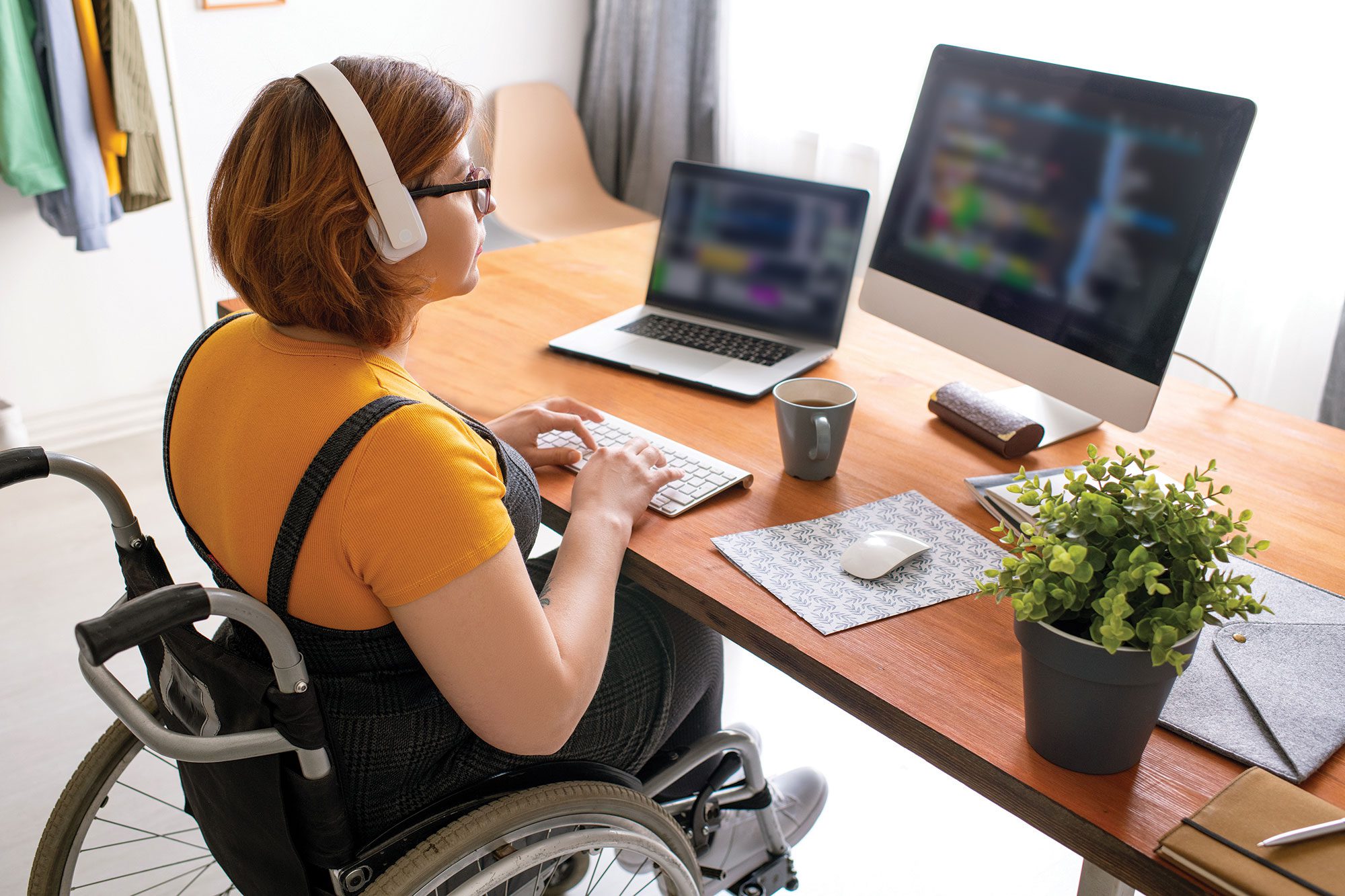 programmer in wheelchair working on her laptop and computer
