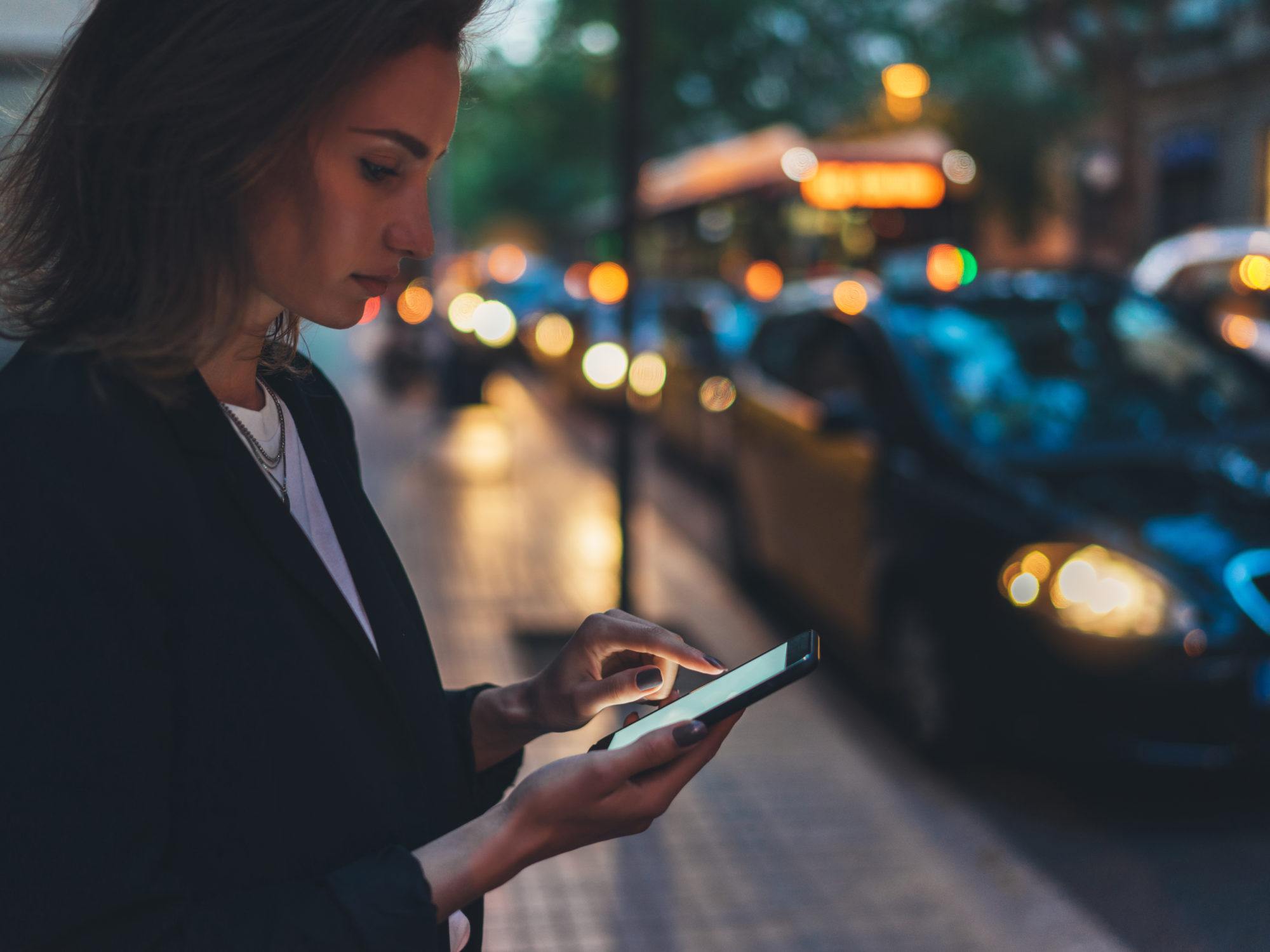 woman tapping on her phone screen in the city