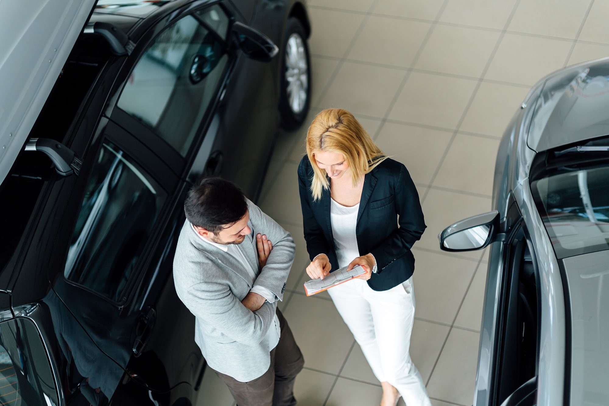 learning and transformation - Woman speaking to a salesman at a car dealership