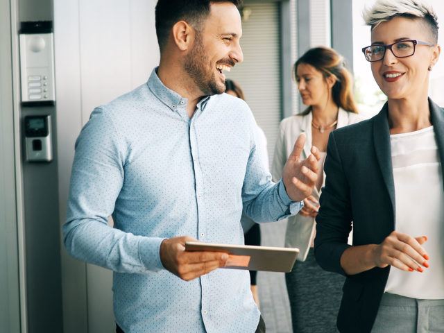 businessman laughing and showing coworker information on tablet