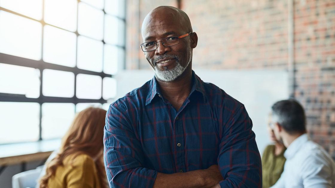 Cropped shot of a businessman standing in the office with his arms folded looking confident and smiling at the camera