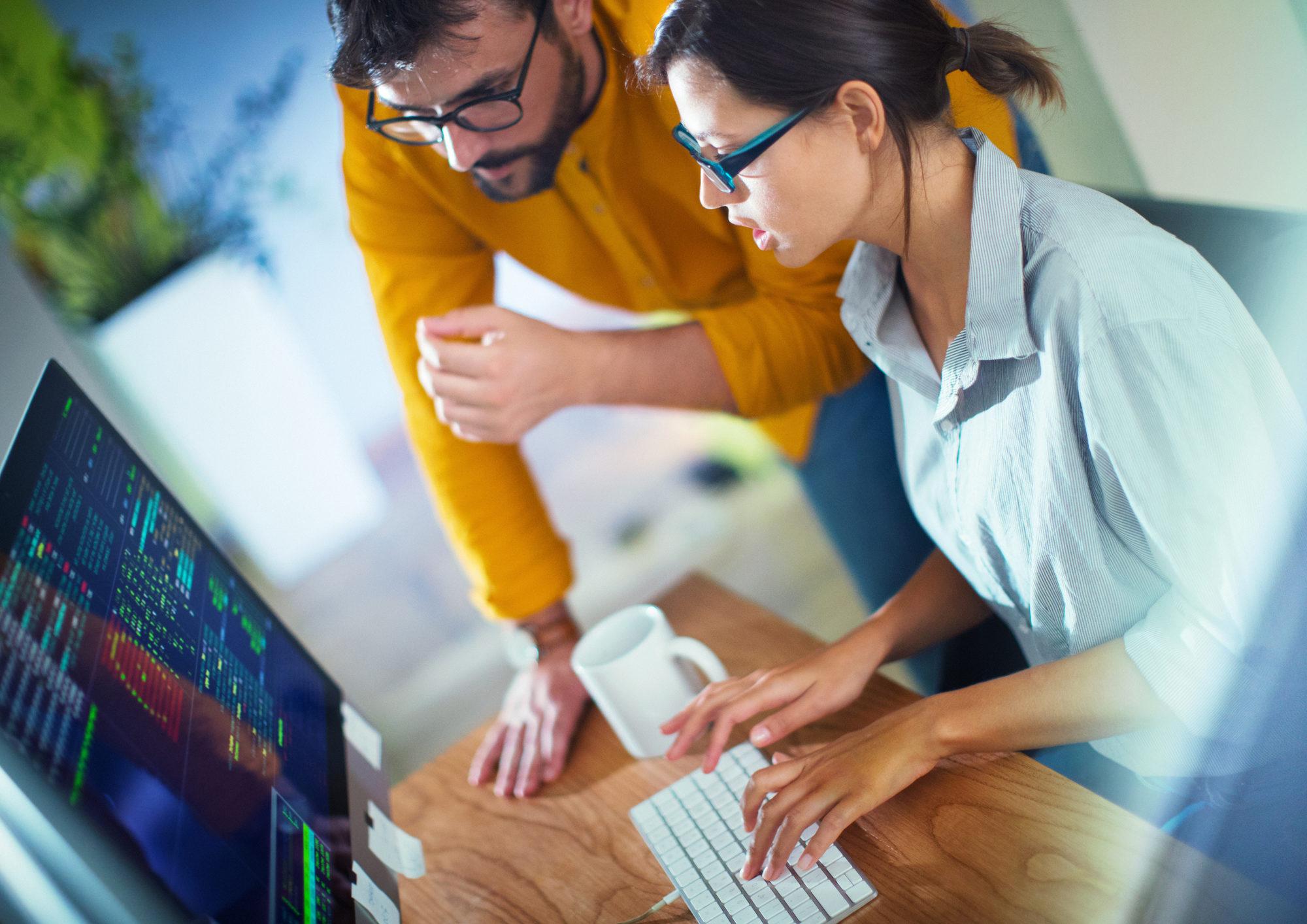 businessman training co-worker on desktop computer