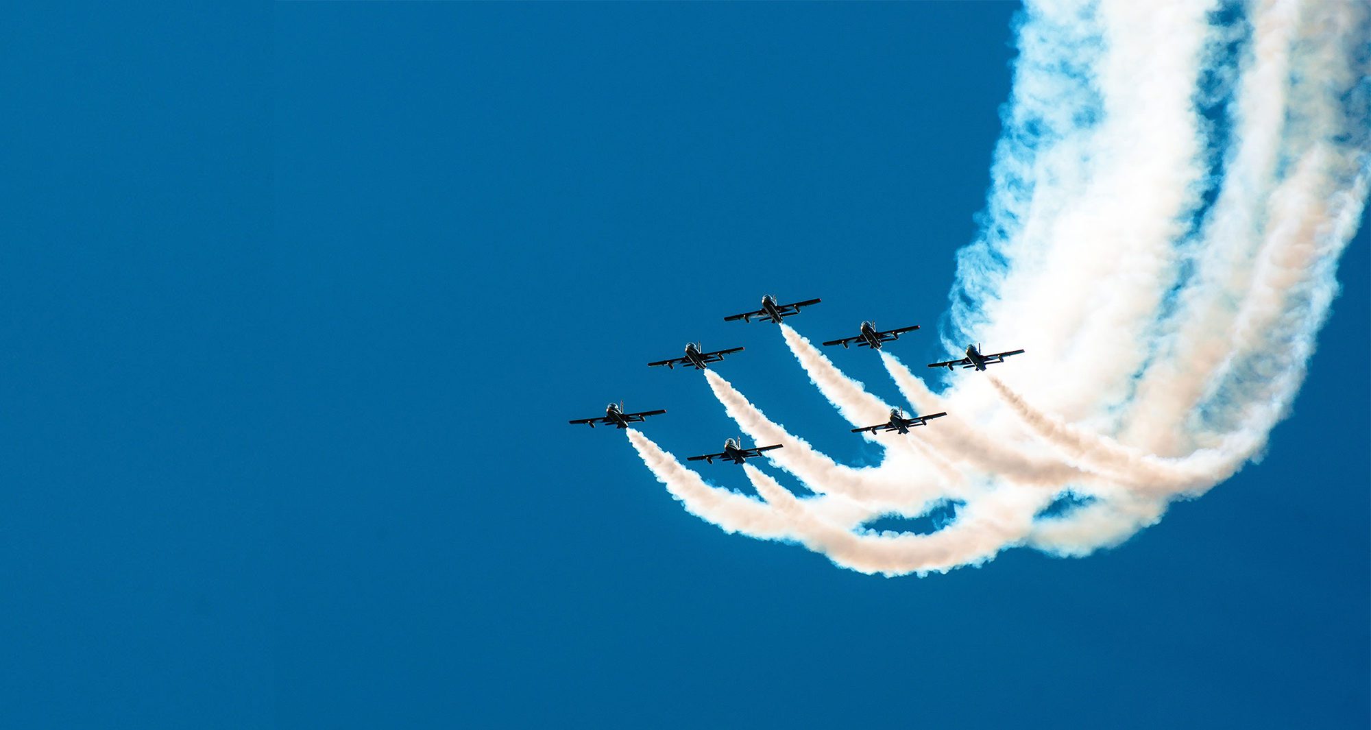 Fighter flies in the smoke in the blue sky aerobatics