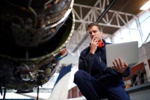 Aircraft engineer in the hangar holding laptop computer