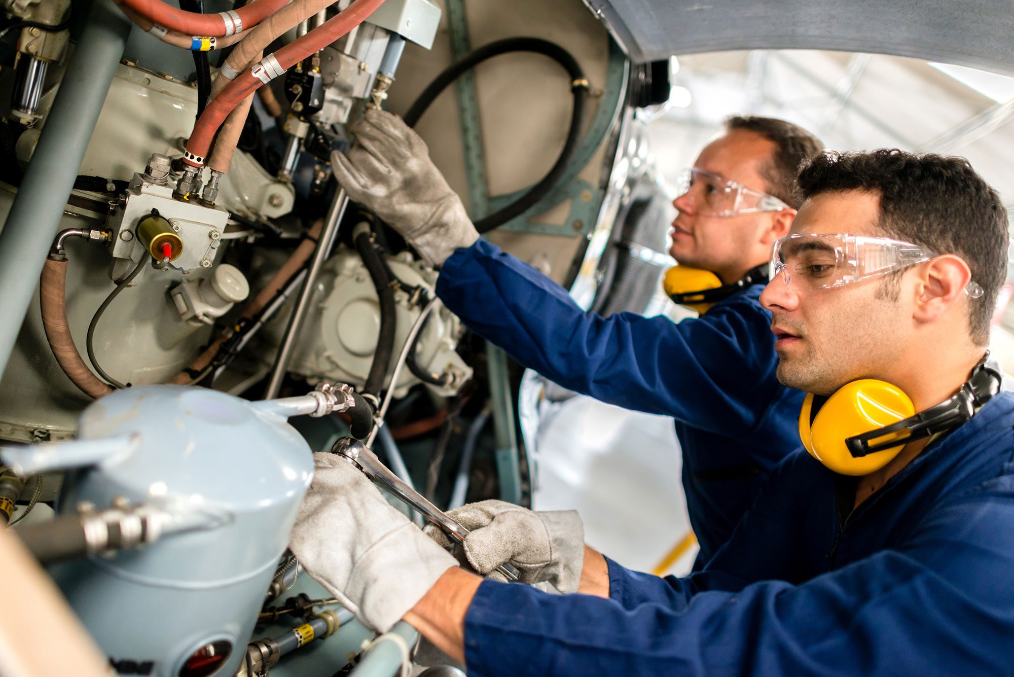 Two mechanics learn to fix a helicopter using an industrial training workstation