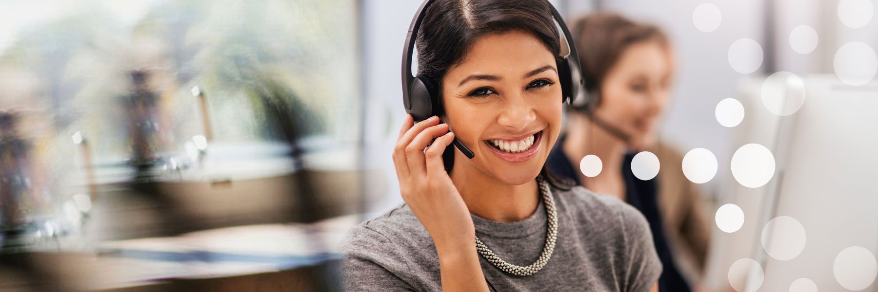 Portrait of a call centre agent working in an office with her colleagues in the background