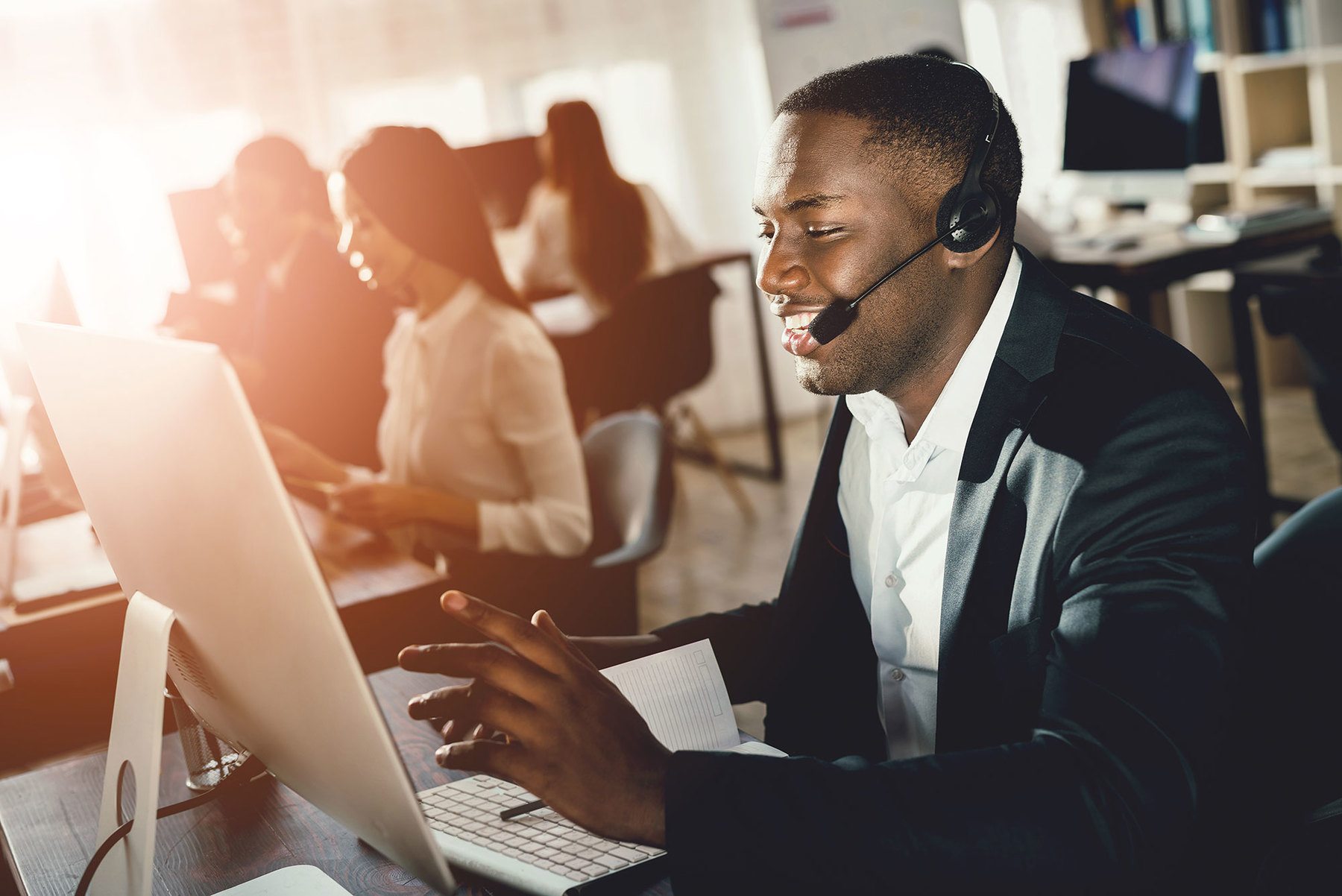Call Centre worker talking to headset while working on his computer