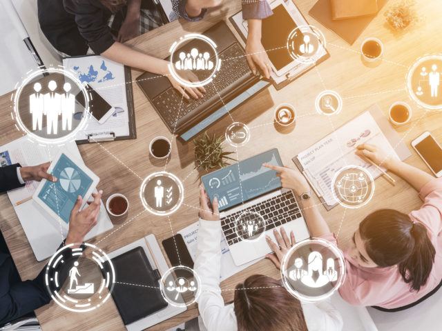 co-workers working on a shared table and Virtual Reality (VR) icons overlaying