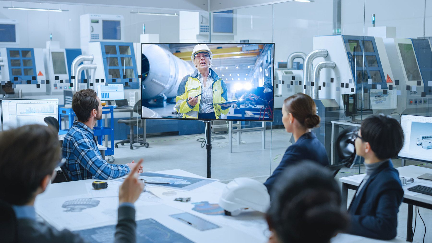 woman on screen talking to business meeting in middle of a laboratory