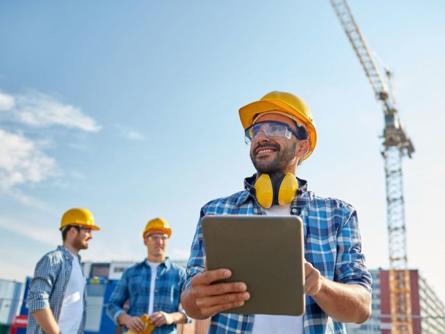 man with hardhat holding a clipboard outside
