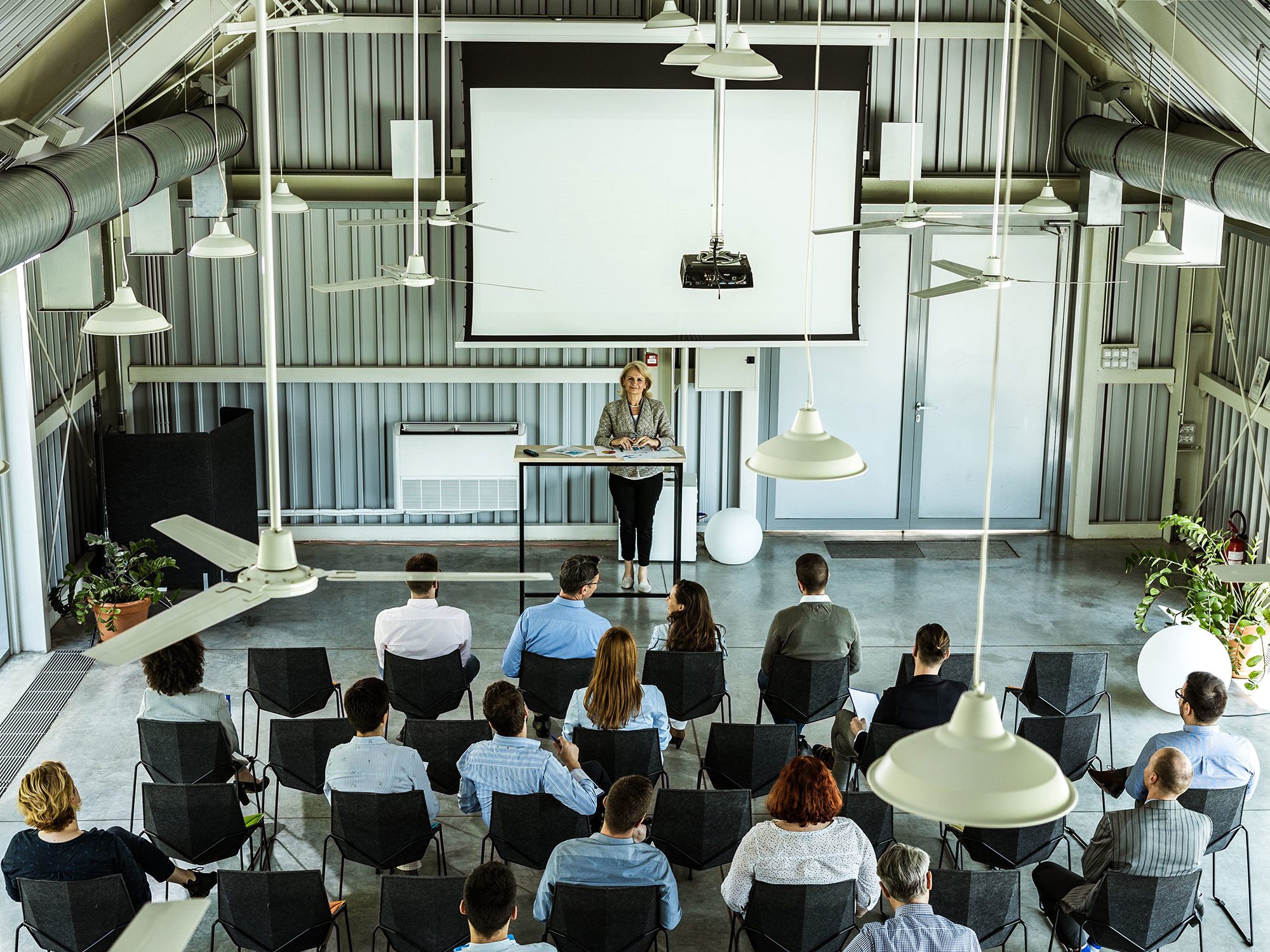 Overhead view of large training class in session in modern high ceiling room